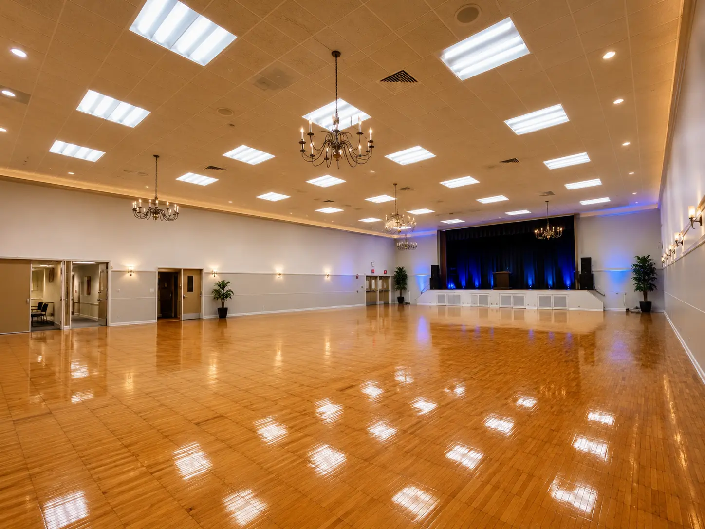 The Grand Ballroom with polished hardwood floor, chandeliers and a stage