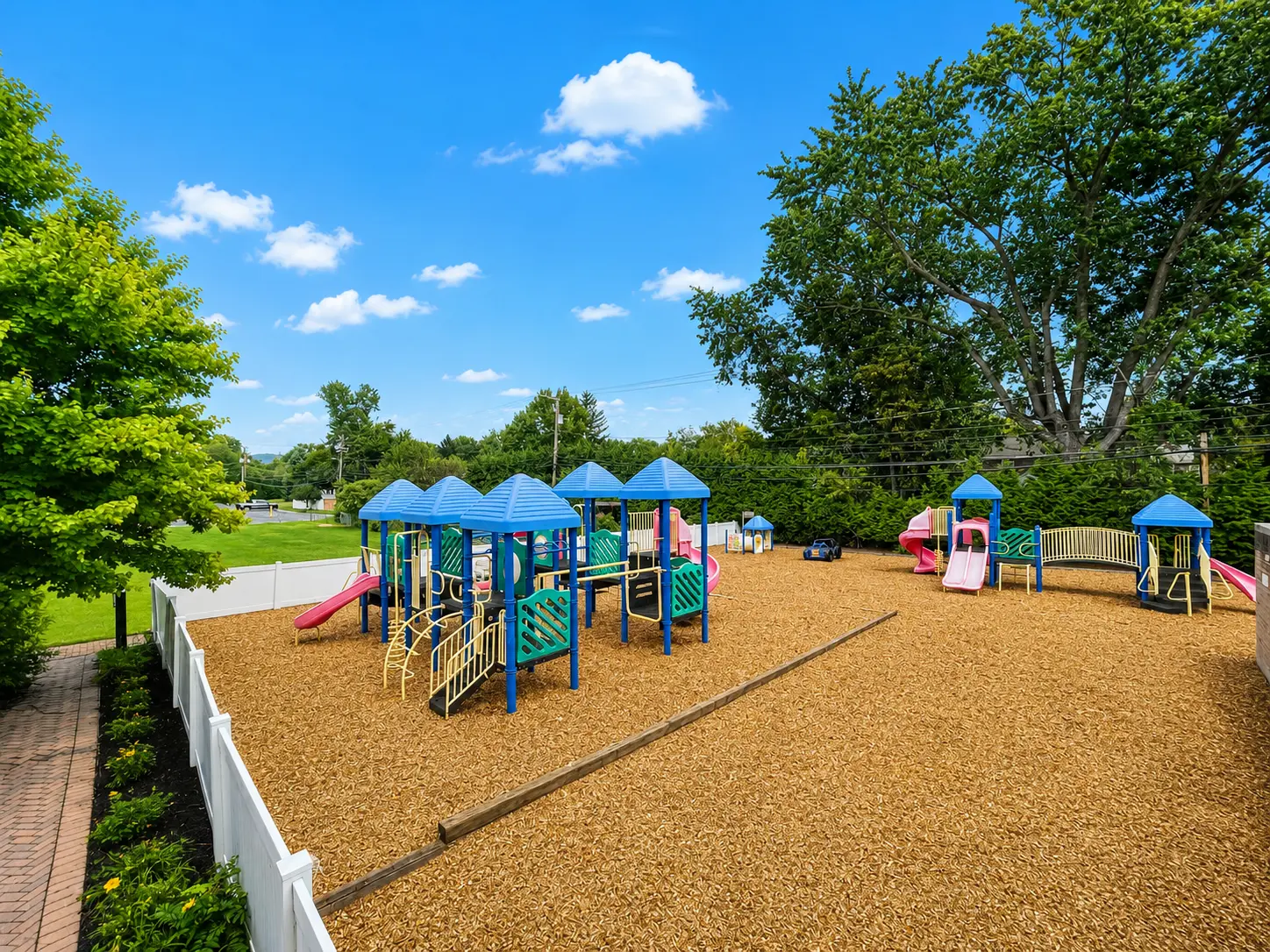 Fenced outdoor playground with slides and climbing structures